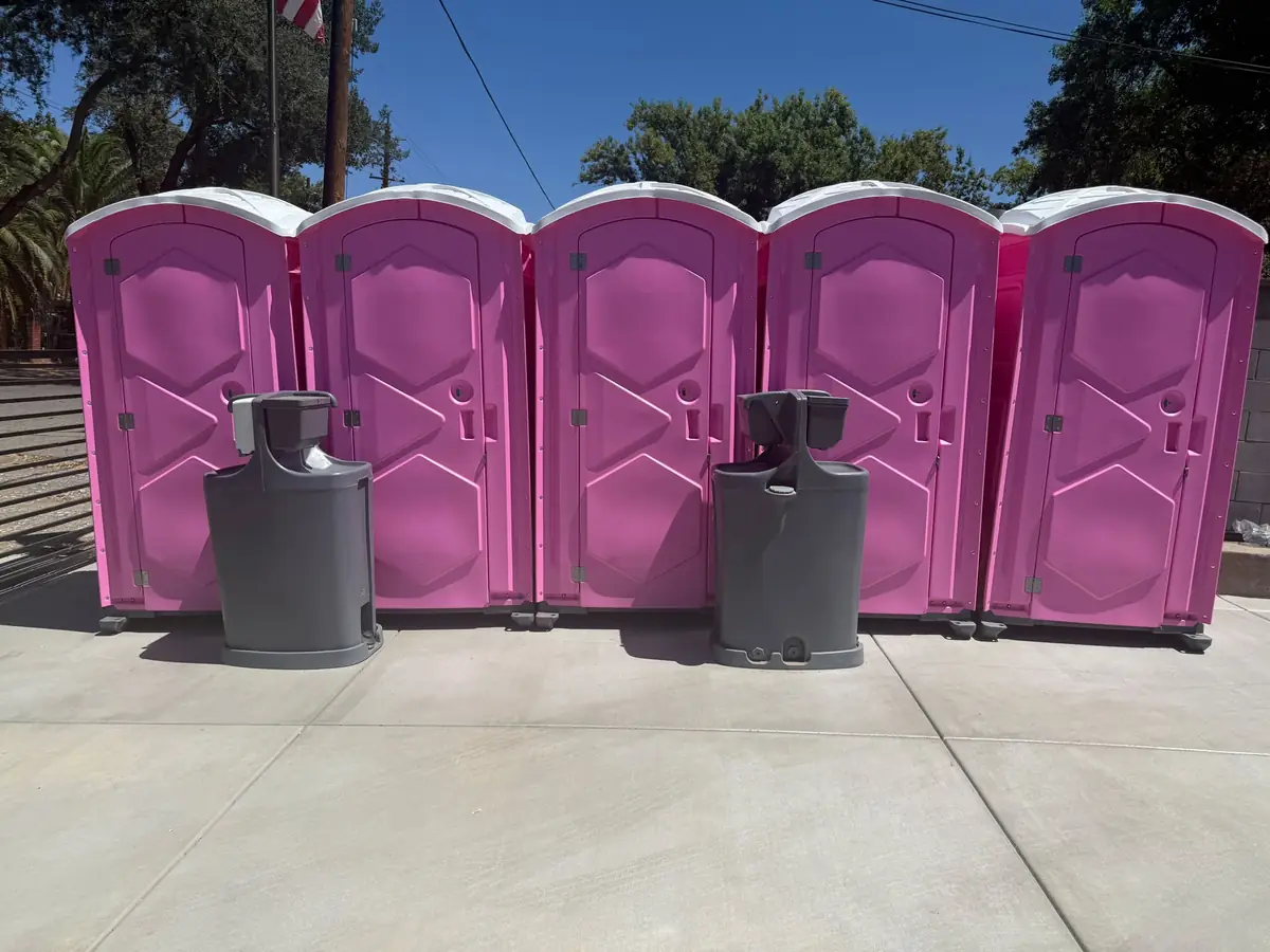 Blue portable toilets set up beside hand wash stations at an outdoor event