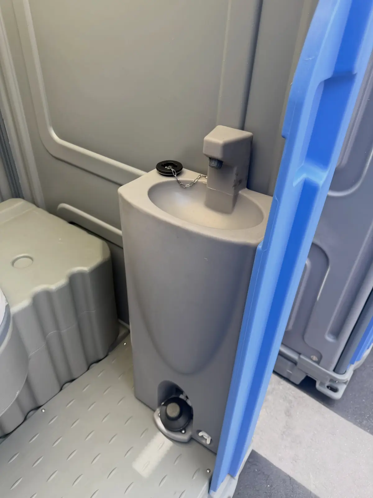 Foot-pump hand sink mounted inside a deluxe portable toilet