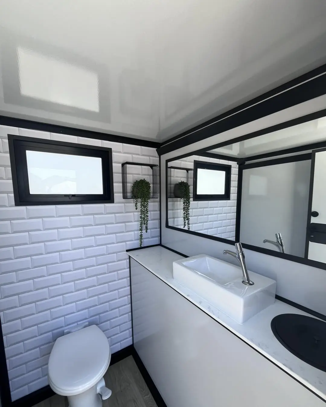 Restroom trailer interior with a tile vanity and toilet