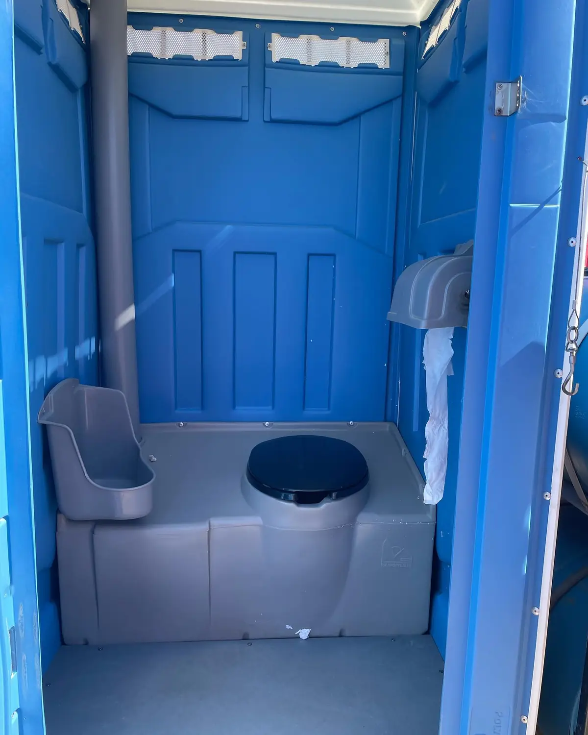 Inside a standard blue porta potty with seat and paper holder
