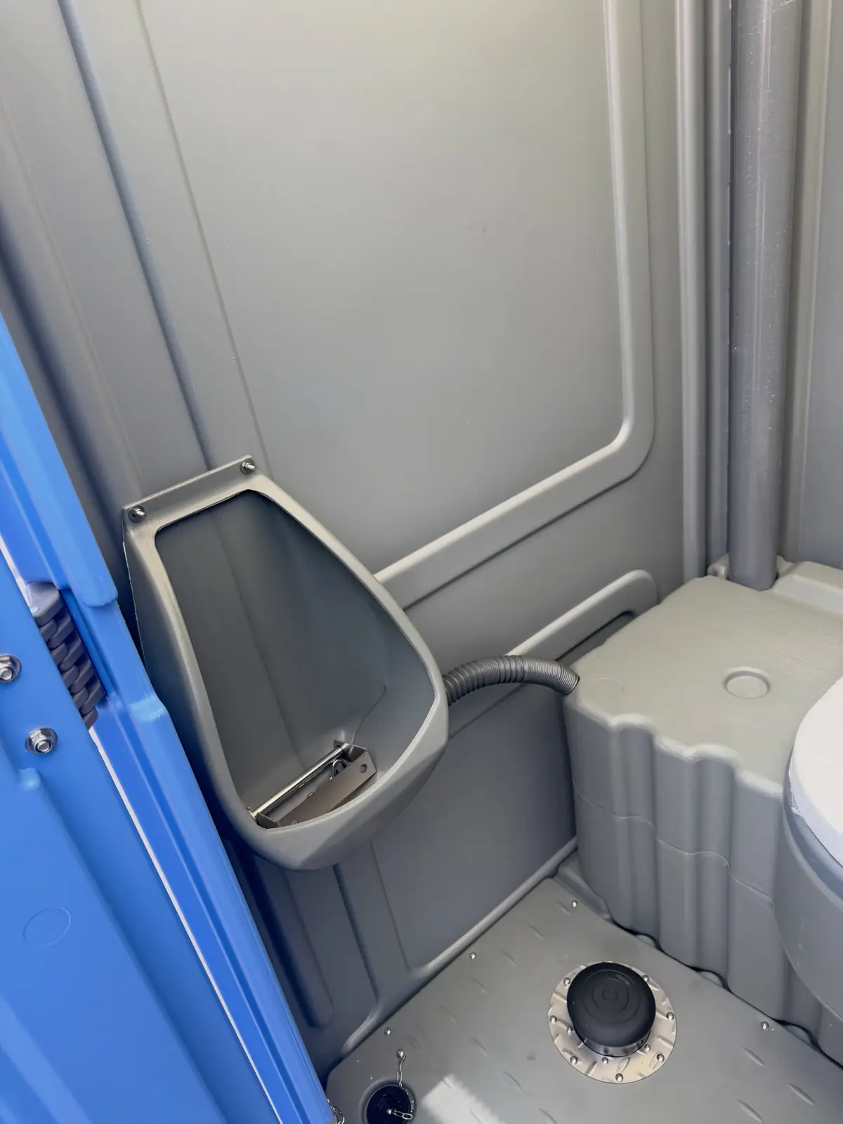 Inside a standard porta potty showing the urinal and vent