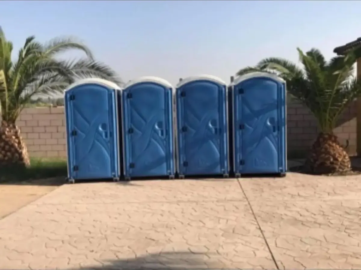 A long row of blue standard portable toilets set up for a large outdoor event