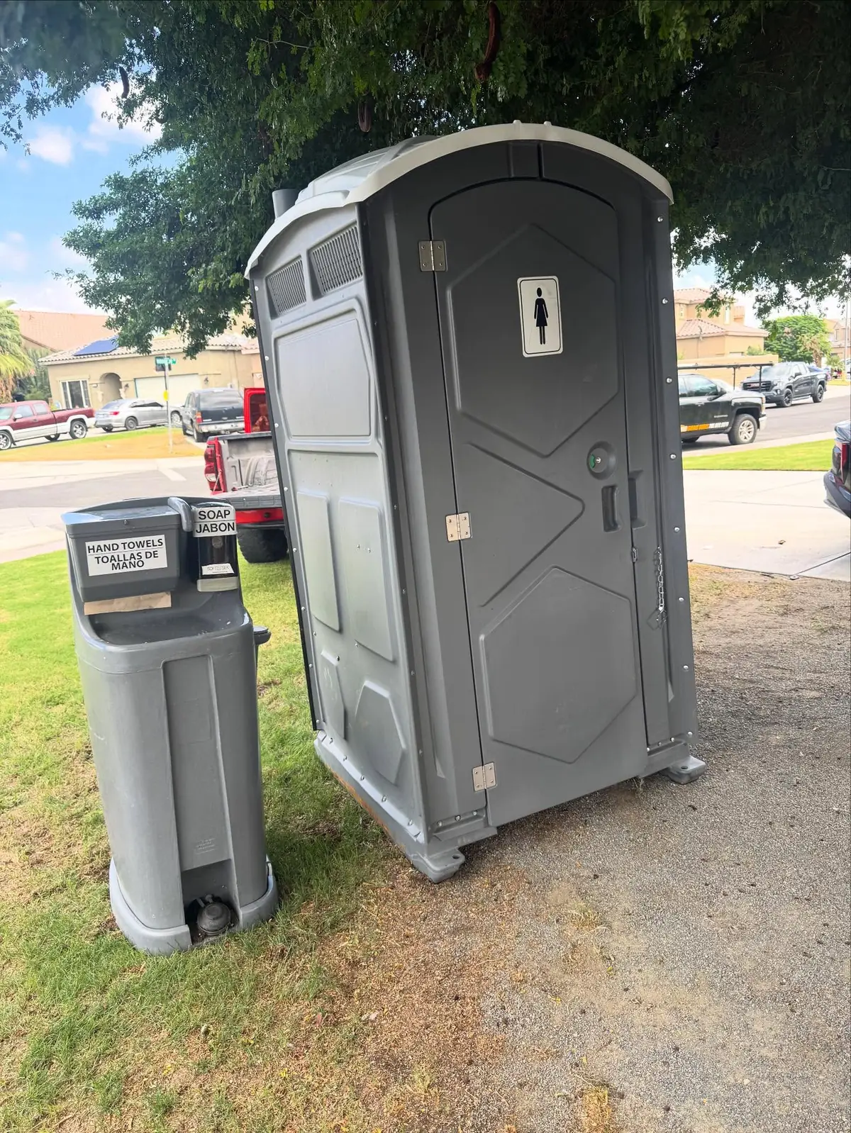 Hand wash station next to a porta potty on a lawn