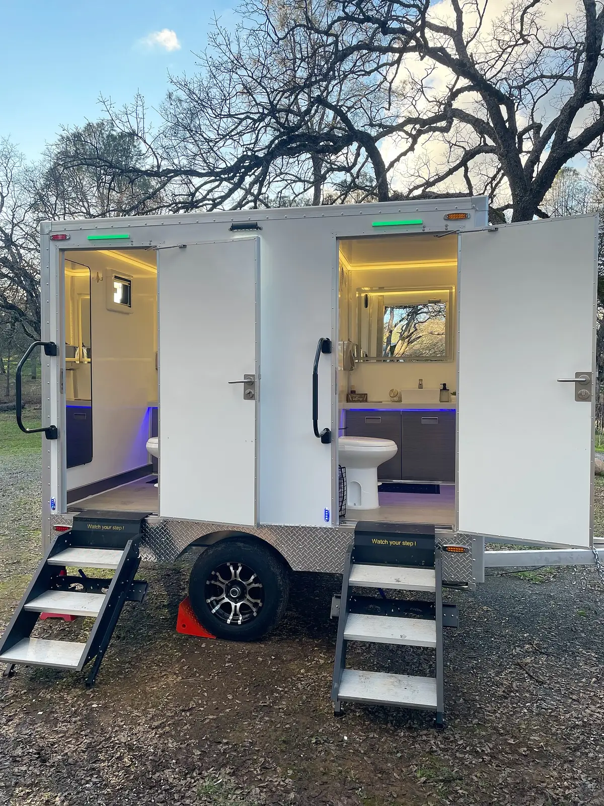 Lit interior of a two-room restroom trailer with vanity and mirror